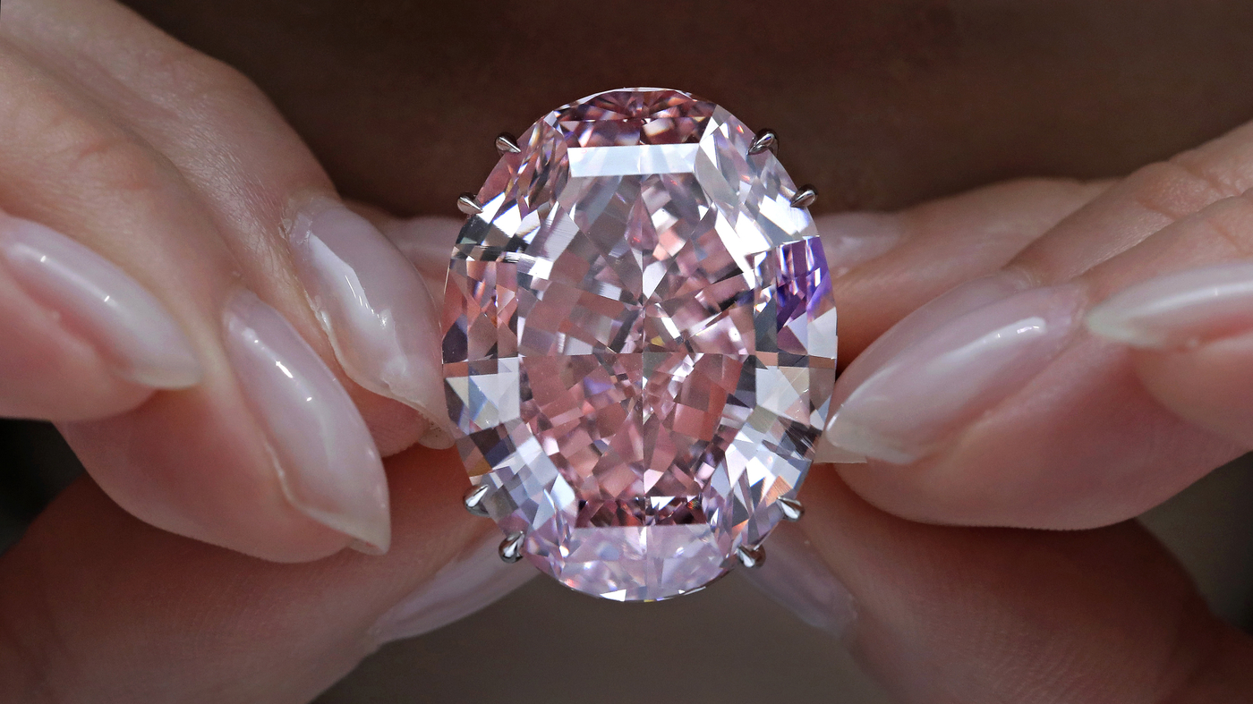 Close-up of the Pink Star Diamond held between fingers, showcasing its intense pink color and flawless cut